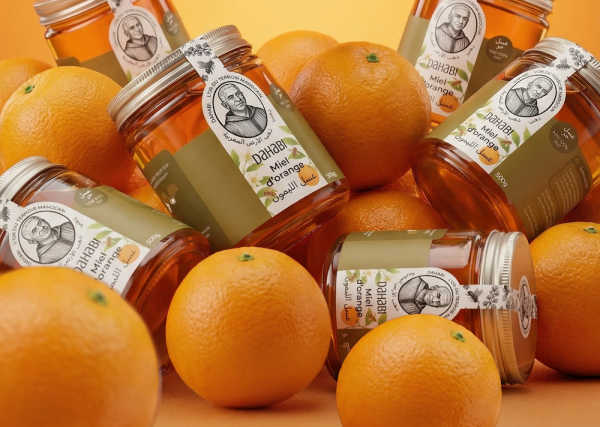 Des pots de miel d'orange a coté de oranges