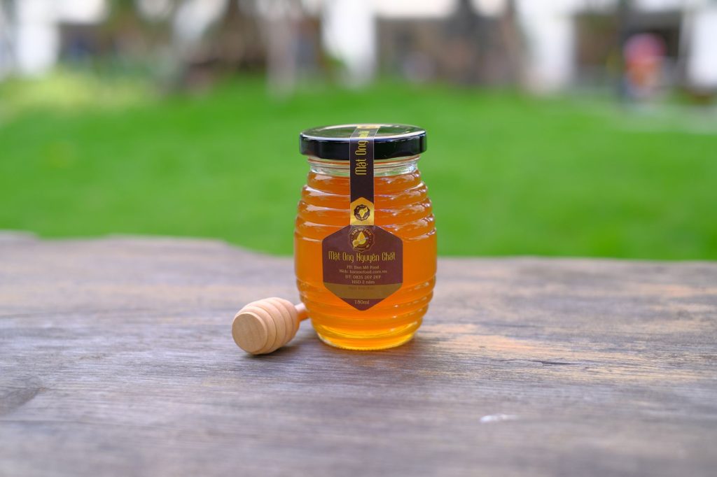 Cuillère de miel au-dessus d'un pot en verre
